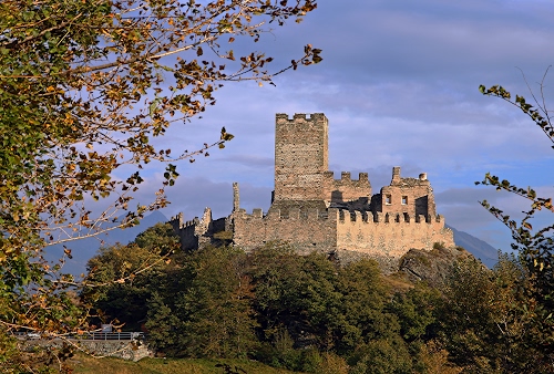 Immagine con alberi, castello, merli, torre, cielo, rami, nuvole, verde, foglie, rocca, piante, ruderi, torri, azzurro, mura, bosco, fortificazioni