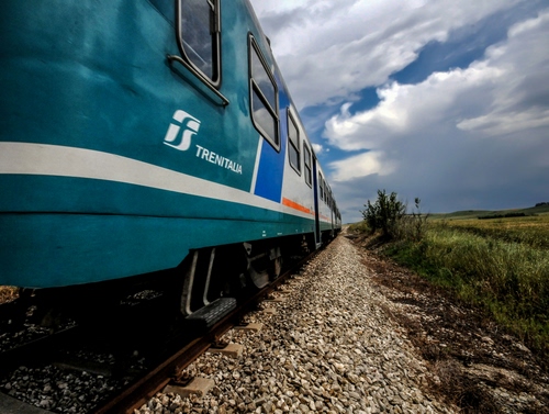 Immagine con treno, nuvole, cielo, massicciata, ferrovia, vagoni, sassi, verde, rotaie, finestrini, binario, binari, vagone, erba, predellino