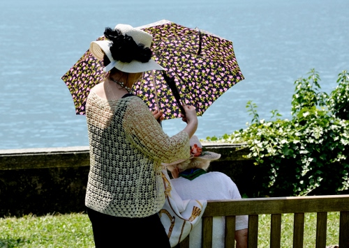 Immagine con ombrello, cappello, panchina, verde, donna, acqua, mare, lago