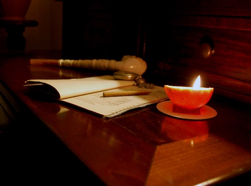 Immagine con candela, pipa, libro, matita, luce, orologio, tavolo, penna, fiamma, quaderno