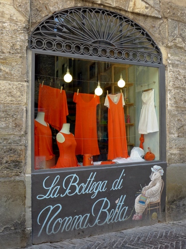 Immagine con vetrina, rosso, vestiti, insegna, bottega, negozio, arancione, abiti, luci