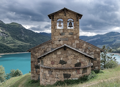 Immagine con lago, campane, campanile, chiesa, nuvole, montagne, verde, pietre, abside, erba, chiesetta, cielo, montagna, campanili, pietra, albero, vela, azzurro, monti, due
