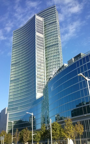 Immagine con alberi, lampioni, finestre, grattacieli, nuvole, cielo, vetri, verde, azzurro, grattacielo, vetro, riflessi, palazzi, riflesso