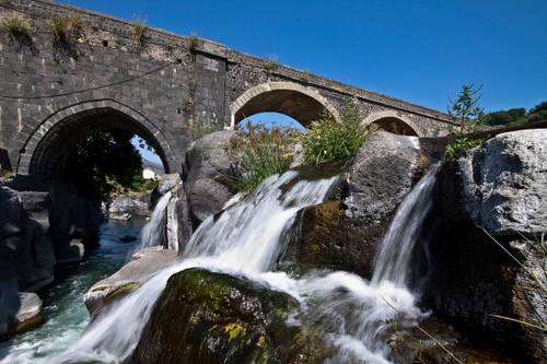 Immagine con ponte, cascata, acqua, fiume, archi, rocce, massi, cielo