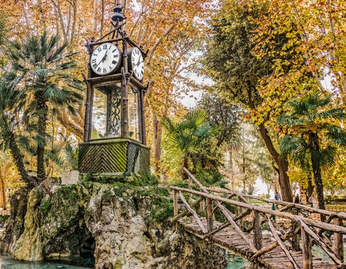 Immagine con orologio, alberi, ponte, legno, autunno, parco, staccionata, giardino, lancette, piante