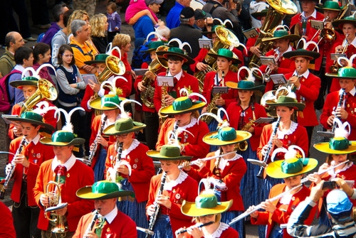 Immagine con banda, cappelli, rosso, strumenti, musicisti, piume, musica, sfilata