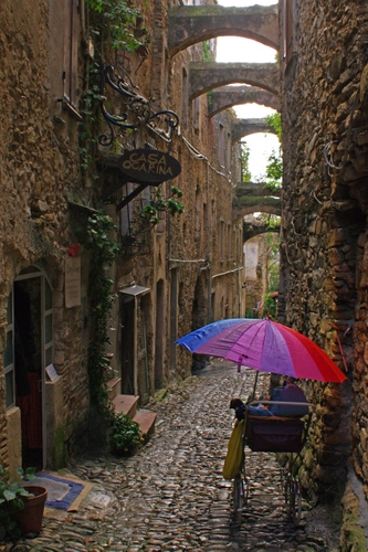 Immagine con vicolo, ombrello, archi, insegna, carrozzina, passeggino, colori, scorcio