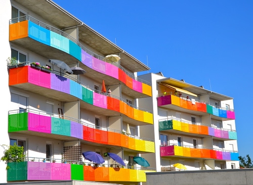 Immagine con balconi, colori, cielo, ombrelloni, multicolore, verde, giallo, azzurro, palazzo, finestre, palazzi, arancione, rosso, case, ringhiere, rosa