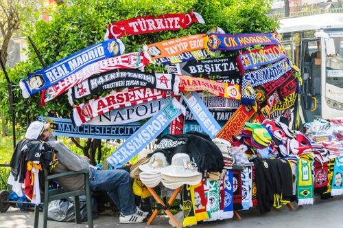 Immagine con sciarpe, cappelli, bancarella, uomo, sedia, calcio, scritte, squadre, sport, colori, striscioni, multicolore