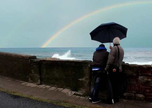 Immagine con mare, arcobaleno, ombrello, persone, onde, muretto, pioggia, due, acqua, parapetto, cielo