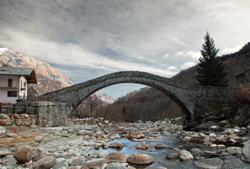 Immagine con ponte, sassi, fiume, arco, acqua, alberi, montagne, casa, albero