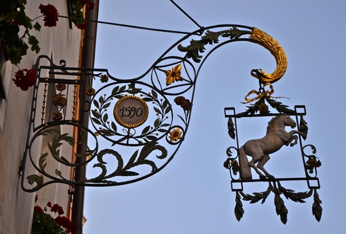 Immagine con insegna, cavallo, ferro, oro, cielo, numeri, foglie, muro, data, tiranti, fiori, blu