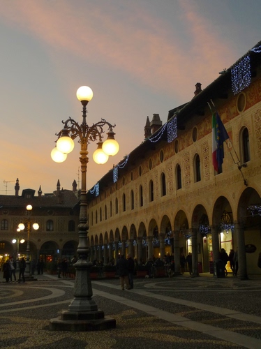 Immagine con lampioni, piazza, luci, finestre, portici, archi, sfere, bandiera, bandiere, sera, portico, palazzi, persone, cielo, tramonto, passanti