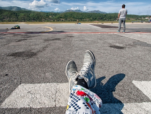 Immagine con scarpe, montagne, nuvole, gambe, asfalto, uomo, persone, ombra, strada, verde, cielo, piedi