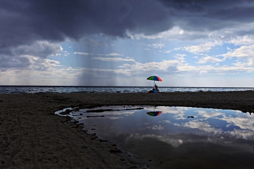 Immagine con mare, ombrellone, sabbia, nuvole, riflesso, cielo, acqua, spiaggia, pioggia
