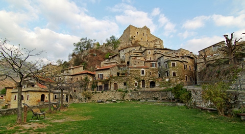 Immagine con alberi, case, prato, panchine, borgo, verde, nuvole, castello, paese, cielo, finestre