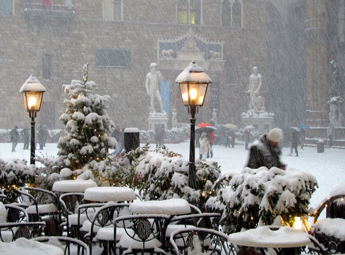 Immagine con neve, statue, lampioni, sedie, tavolini, inverno, firenze, persone, piazza, luci, bianco, palazzo, alberi, ombrelli, passanti, albero, finestre