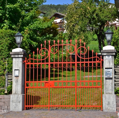 Immagine con cancello, lampioni, rosso, alberi, verde, colonne, erba, citofono, piante, ferro, villa, prato, numero, case, parco, punte, giardino, casa, civico, piloni