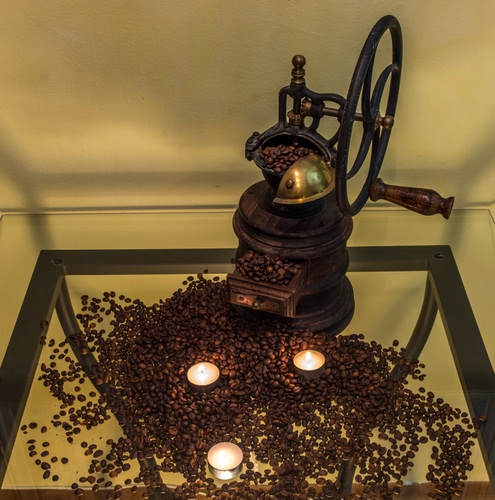 Immagine con caffè, chicchi, macinino, ruota, candele, marrone, manovella, vetro, luci, tavolino