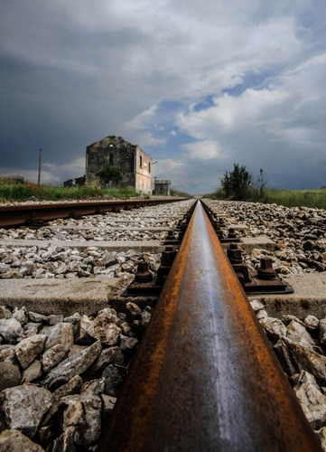 Immagine con nuvole, cielo, ferrovia, ruggine, ferro, rudere, sassi, pietre, binario, rotaie, binari, bulloni, stazione, traversine, massicciata, casa, piante, erba, verde, rotaia, legno, traverse, metallo