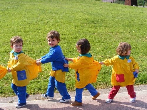 Immagine con giallo, bambini, prato, verde, blu, fila, quattro, erba, grembiuli