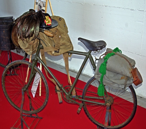 Immagine con bicicletta, cappello, piume, ruote, divisa, sella, bersagliere, bici, zaino, rosso, verde, guerra, sellino