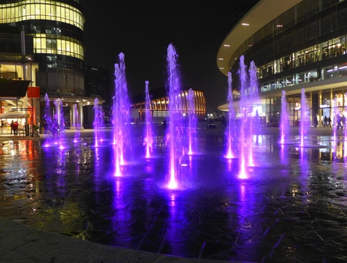 Immagine con fontana, viola, notturno, acqua, zampilli, spruzzi, getti, luci, palazzi, piazza