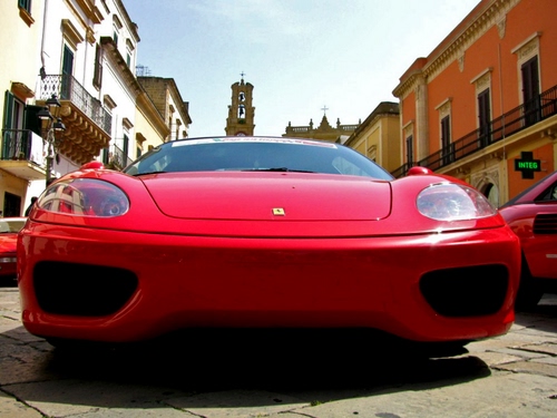 Immagine con ferrari, rosso, automobile, fanali, campanile, auto, strada, macchina, rossa, fari, sportiva, cofano, balconi, cielo, finestre, case