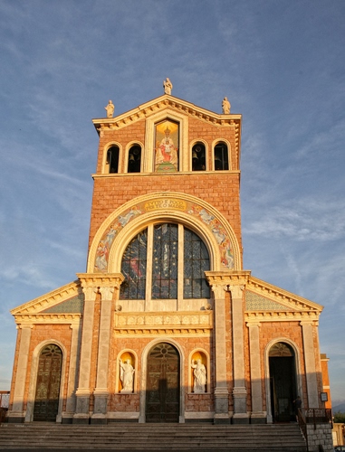 Immagine con chiesa, vetrata, statue, facciata, campane, porte, scalinata, cielo