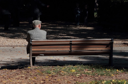 Immagine con panchina, cappello, uomo, seduto, parco, ombra, anziano, strada, foglie, legno, persona