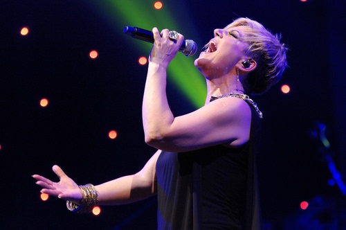 Immagine con microfono, cantante, donna, musica, luci, mani, gioielli, nero