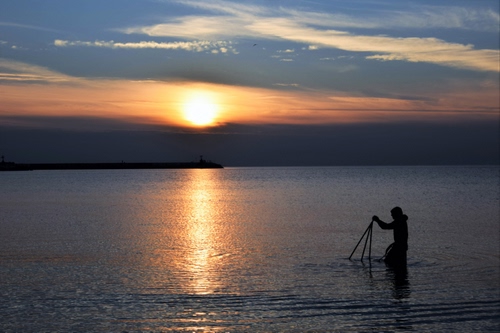 Immagine con mare, tramonto, sole, riflesso, pescatore, nuvole, acqua, uomo