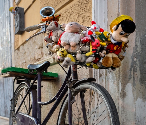 Immagine con bicicletta, pinocchio, ruote, pupazzi, peluche, giocattoli, cestino, muro