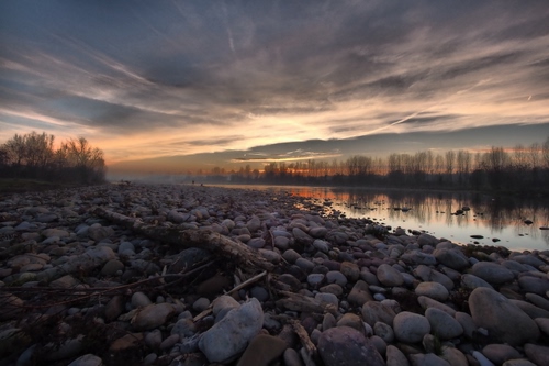 Immagine con sassi, fiume, tramonto, alberi, nuvole, acqua, greto, ciottoli, silenzio