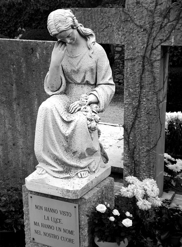 Immagine con fiori, statua, croce, bianconero, cimitero, tomba, scritta, lapide, marmo, vasi, mani, capelli, monumento, mano, piante