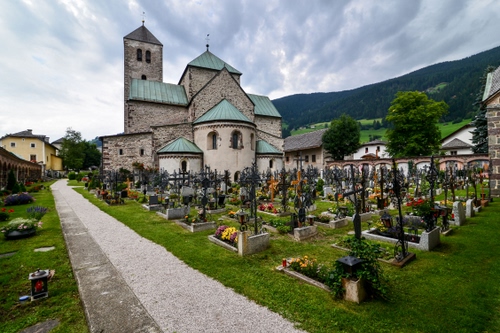 Immagine con cimitero, tombe, chiesa, croci, fiori, nuvole, campanile