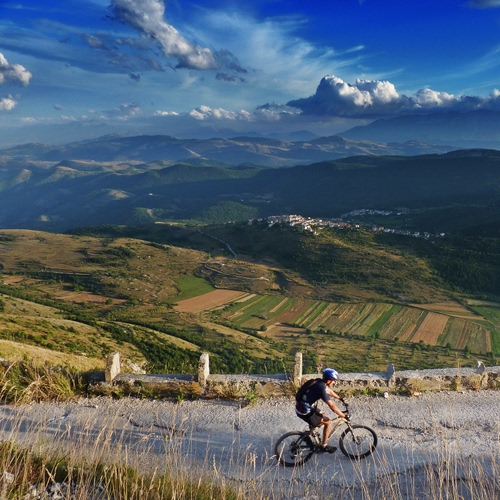 Immagine con nuvole, cielo, strada, bicicletta, ciclista, panorama, erba, campi, verde, colline, sport, azzurro, paesaggio, montagna, montagne