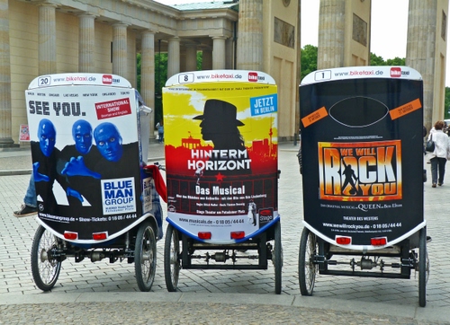 Immagine con pubblicità, colonne, ruote, piazza, tre, carrozze, nero, rosso, colonnato, giallo, scritte, tricicli, risciò, trasporto, persone