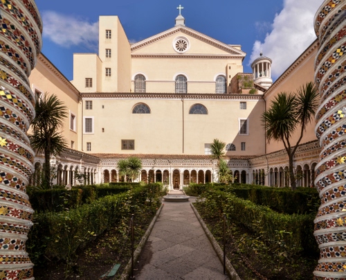 Immagine con colonne, chiesa, chiostro, croce, archi, finestre, alberi, giardino, nuvole, cielo, aiuole, siepe, verde, siepi, rosone, convento, mosaico, palme