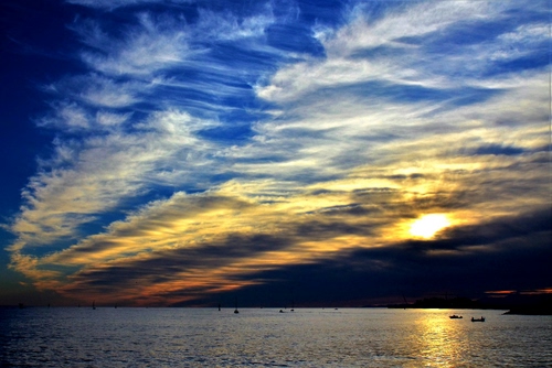 Immagine con nuvole, mare, barche, tramonto, cielo, sole, controluce, acqua, blu, riflesso