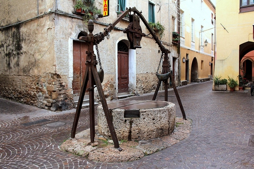 Immagine con pozzo, piazza, ferro, porte, strada, carrucola, catena, portoni, vasi