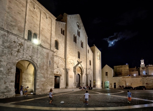 Immagine con chiesa, bambini, piazza, notte, luna, finestre, notturno, giocare, archi, nuvole, gioco, arco, sera, porte, case, portone, cielo