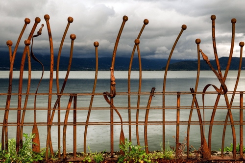 Immagine con nuvole, acqua, cielo, ferro, ringhiera, erba, lago, mare, metallo, montagne, balaustra, scultura