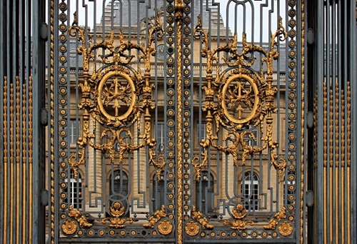 Immagine con cancello, oro, ferro, palazzo, finestre, grigio, porte, stemmi, edificio, ovale, ovali, disegni, colonne, foglie, cerchi, fregi, metallo