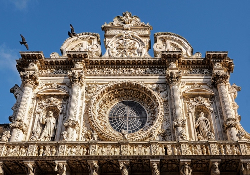 Immagine con rosone, statue, cielo, barocco, uccelli, azzurro, colonne, chiesa, vetrata, balaustra, cerchio, colombi, facciata, cattedrale, sculture, piccioni