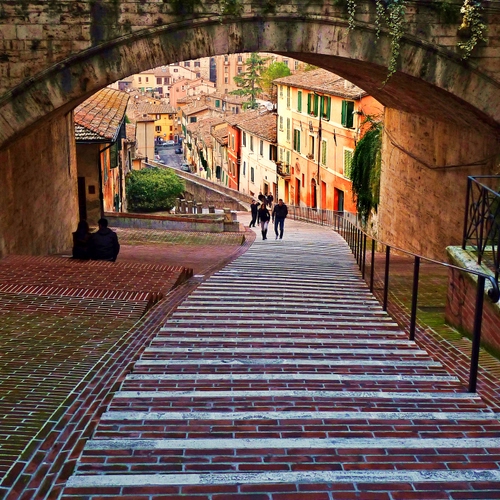 Immagine con case, arco, persone, scorcio, discesa, finestre, vicolo, mattoni, ringhiera, scale, tetti, colori, porte, paese, scalinata