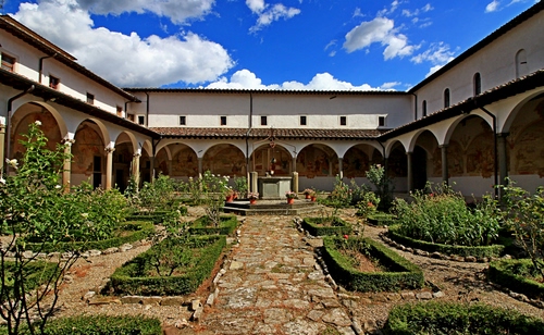 Immagine con aiuole, nuvole, cielo, chiostro, colonne, pozzo, archi, piante, verde, giardino, finestre, fiori, azzurro, vasi, siepi, bianco, porticato, arco