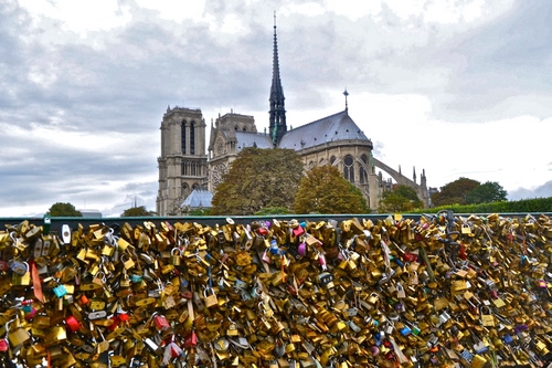 Immagine con chiesa, lucchetti, cielo, campanile, alberi, nuvole, croce, parigi, tanti, cattedrale, metallo, finestre, guglia, torri