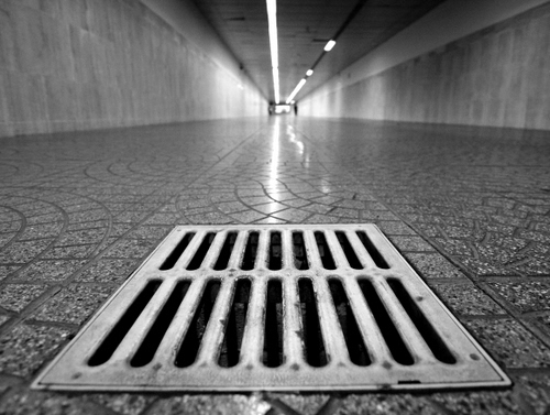 Immagine con tombino, pavimento, tunnel, luci, prospettiva, corridoio, galleria, feritoie, grata, griglia, piastrelle, ferro, riflessi, mattoni, bianconero